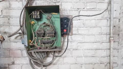 Old electrical panel on the wall of the house. Electric cables stick out from Foto stock