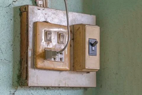 The old electrical plug next to the cream wall. Stock Photos
