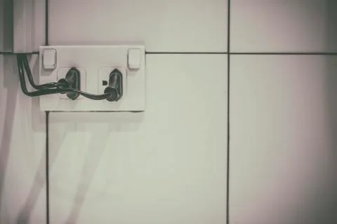 The old electrical plug next to the cream wall. Stock Photos