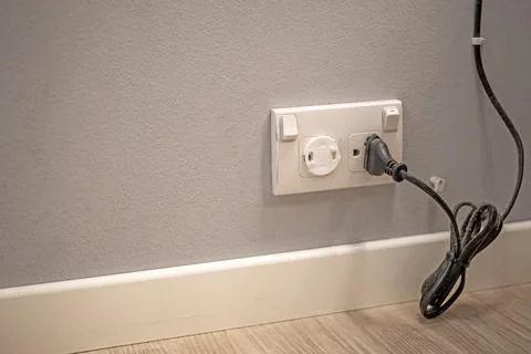 The old electrical plug next to the cream wall. Stock Photos