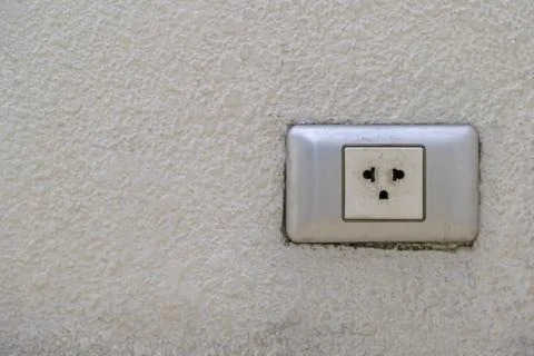 The old electrical plug next to the cream wall. Stock Photos