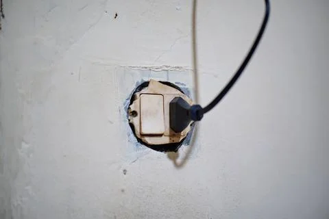 Old electrical socket and switch with connected cable on a damaged and cracked Stock Photos