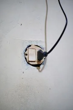 Old electrical socket and switch with connected cable on a damaged and cracked Stock Photos