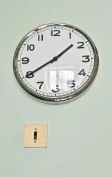 Old electrical switch and a modern clock on the wall Stock Photos