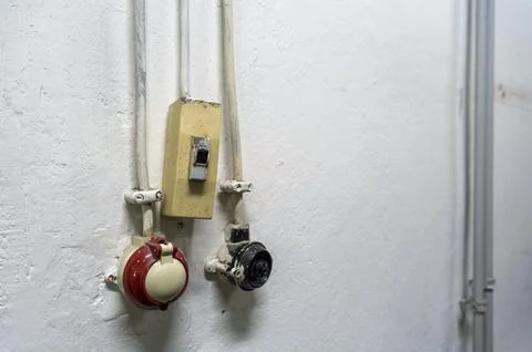 Old electrical switch and sockets located on a plain white wall in an indoo.. Stock Photos