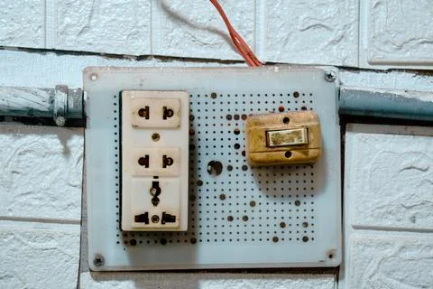 Old electrical switchboard mounted on a tiled wall Stock Photos