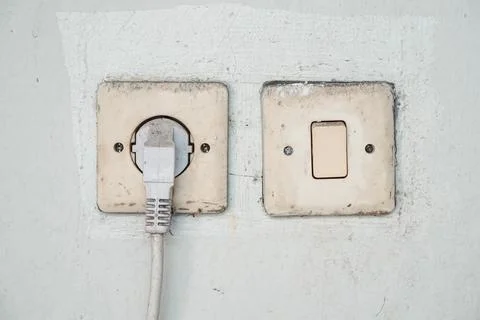 Old Electrical Wall Socket and Light Switch with Plug Connected 스톡 사진