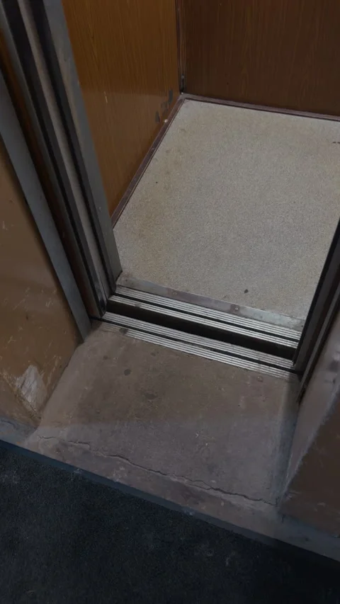 Old elevator interior with worn wood panels, narrow doorway, dim light, and Stock Footage 342502929