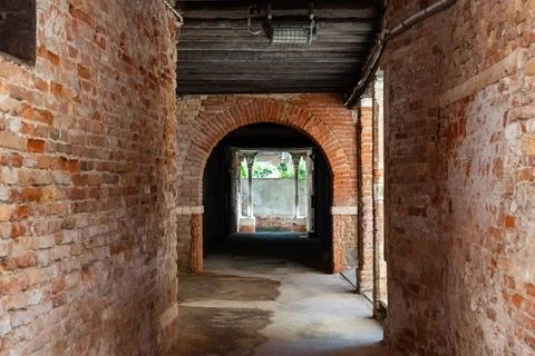Old, empty arched hall or passage made of bricks with wooden beams in Venice Stock Photos