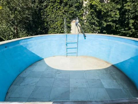 Old empty swimming pool with blue walls. Pool without water, dried up pool Stock Photos