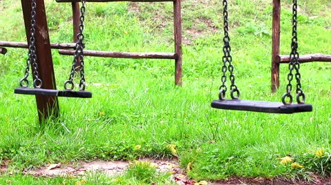 Old empty swings with chains swaying at playground for child, moved from wind Stock Footage 56630122