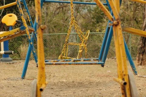 Old empty swings with chains swaying at playground 스톡 사진