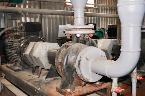 Old engine with a connected pump on the water supply pipeline. Stock Photos