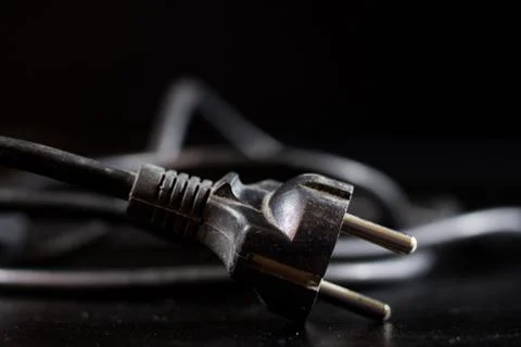 Old entangled cables, electronics and old cable connectors on a black table. Stock Photos