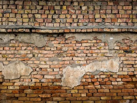 Old eroded brick wall with damaged plaster leftovers Stock Photos