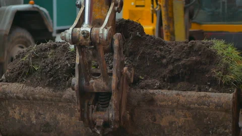Old excavator digs the ground. Digger loading earth in slow motion Stock Footage 231223301