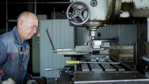 Old experienced plant worker in protective uniform drilling a piece of metal on Stock Footage 94994316