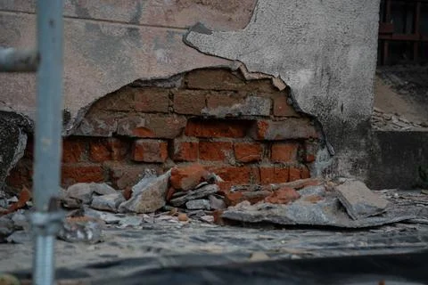 Old, fallen-off plaster from a brick building. Red brick behind the plaster Stock Photos
