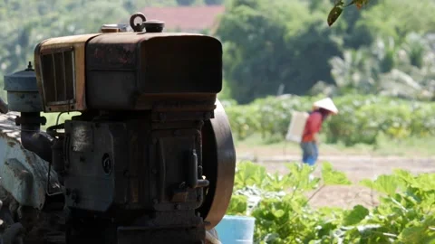 Old farm machine at the edge of a green field with a farmer working in the backg Stock Footage 340150243
