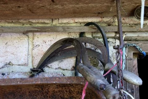 Old farm tools hang on a wall in rustic shed showing wear and use over time in a Foto stock