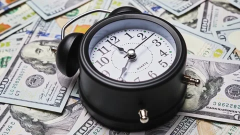 Old fashioned alarm clock with bells on background of dollar banknotes. 库存影片 328462479