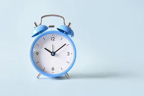 Old-fashioned blue alarm clock on blue background. Stock Photos