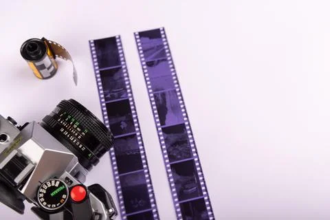 Old-fashioned camera next to 35mm film rolls and developed film, laid out o.. Stock Photos