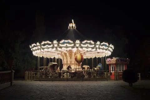 Old fashioned carousel backlit in a night park, autumn background Stock Photos
