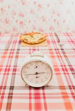An old fashioned clock on a table with a pizza Foto stock