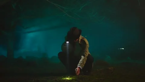 Old fashioned detective a man in a hat with a flashlight in his hands in a dark Stock Footage 245894522