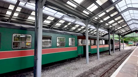 Old fashioned green train car with a red stripe stopping at the Alston station Stock Footage 339913033