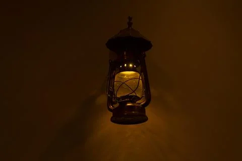 Old fashioned lantern with flame on a brown wooden wall Foto stock