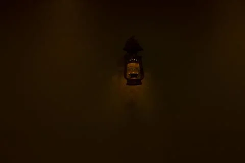 Old fashioned lantern with flame on a brown wooden wall 스톡 사진