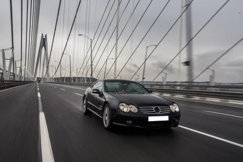 Old fashioned model black car in a rainy weather on the bridge Stock Photos