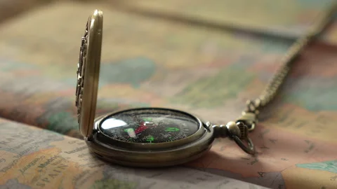 Old fashioned pocket watch compass with a chain lies open on a geographical map Video stock 319518687