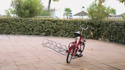 Old-fashioned red bicycle parked on the square with no people in cloudy day Stock Footage 162664796