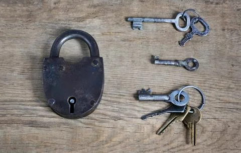 Old fashioned rusty lock with keys on wooden surface Stock Photos