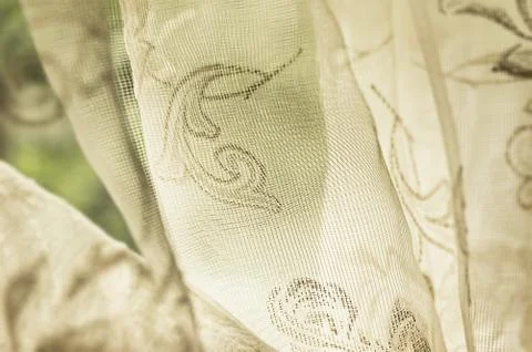 Old fashioned sheer fabric patterned curtain hanging on window in natural light Stock Photos