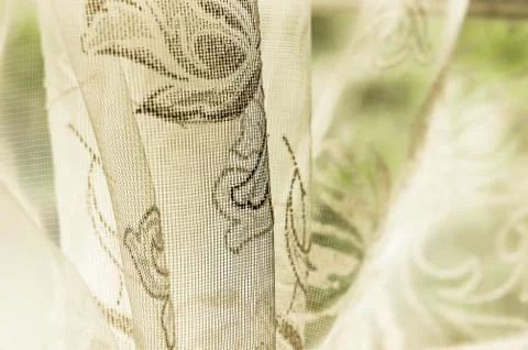 Old fashioned sheer fabric patterned curtain hanging on window in natural light Stock Photos