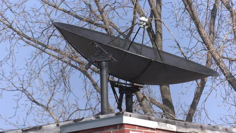 Old fashioned TV satellite dish on house roof for television signals reception Stock Footage 149864773