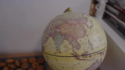Old fashioned world globe with a focus on asia rotating slowly in a cozy room, Stock Footage 328984312