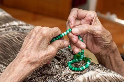 Old female hands holding green praying beads Stock Photos