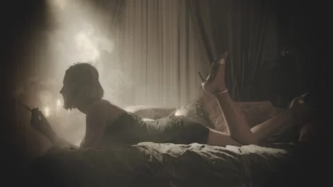 Old film 20s style black and white color. Retro lady lying on bed long legs wavi Stock Footage 291529853