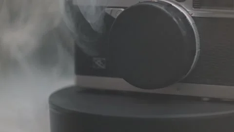 Old film camera macro with yellow light spins around its axis in smoke on Stock Footage 281098063
