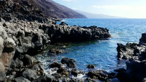 Old fixed lava stream in a calm blue ocean Video stock 137133084