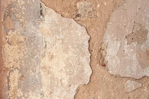 Old flaky white paint peeling off a grungy cracked wall. Cracks, scrapes, pee Stock Photos