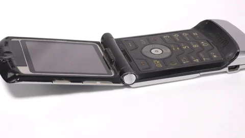 An old flip phone on white base and surface moving Stock Footage 111887755