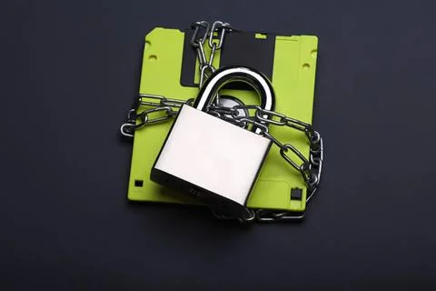 Old floppy disk with padlock and chain on dark background Stock Photos