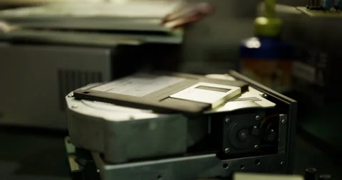 Old floppy disk placed on a classic hard drive in a tech workspace Stock Footage 305769691