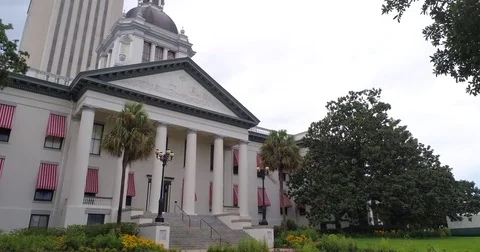 Old Florida Capitol drone shot slow boom up, arc-right, Flags point of interest Stock Footage 79321670